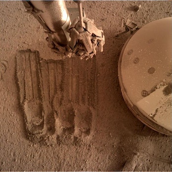 In another recent image, the Survey uses its robotic arms to scratch some of the regolith in the environment...