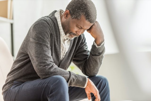 selective focus of depressed african american man sitting with his head down