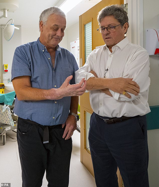 Pictured: Mr Cahill, who was the first person in the UK to have a hand transplant in 2012, with surgeon Simon Kay, at Leeds General Infirmary