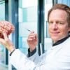 This shows the researcher holding a brain model and a syringe