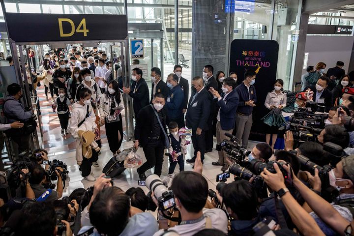 Members of the media record travelers arriving at the Suvarnabhumi Airport in Bangkok on Monday after China removed COVID-19 travel restrictions.