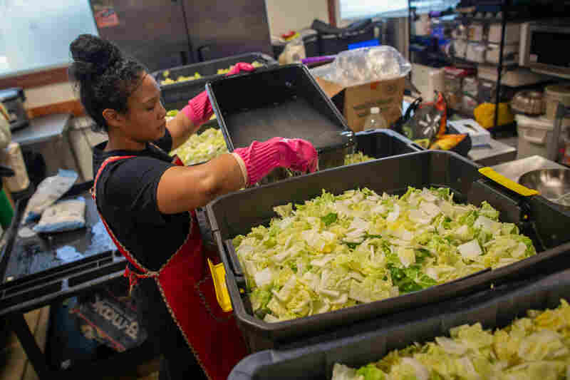 Cunningham pours brine into containers of chopped cabbage. The brine will sit with the cabbage overnight during the two-day process of making kimchi.